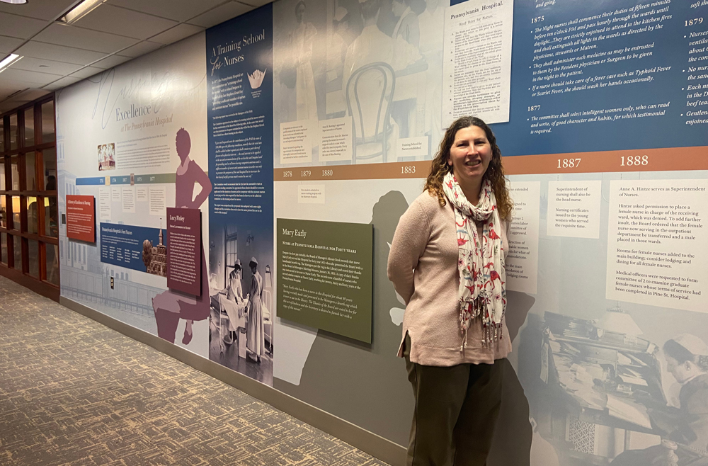 Stacey Peeples stands in front of the Nursing Excellence at the Pennsylvania Hospital exhibit